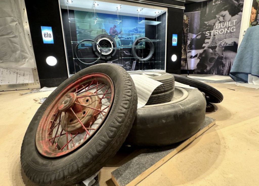 Tires dominate the center of an exhibit space on the middle floor which features some Akron’s well-known and lesser-known history. The display case in the background shows a mural from The Rubber Room from the Portage Hotel. (Kevin Dilley / Signal Akron)